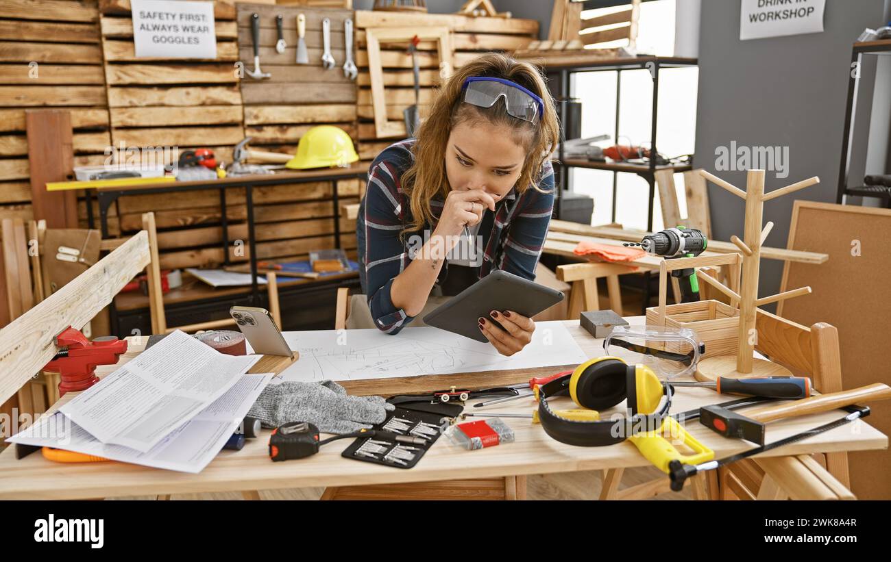 Beautiful young hispanic woman carpenter masterfully utilizes touchpad ...