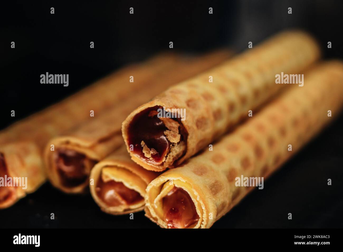 Sweet wafer rolls with chocolate condensed milk on dark background