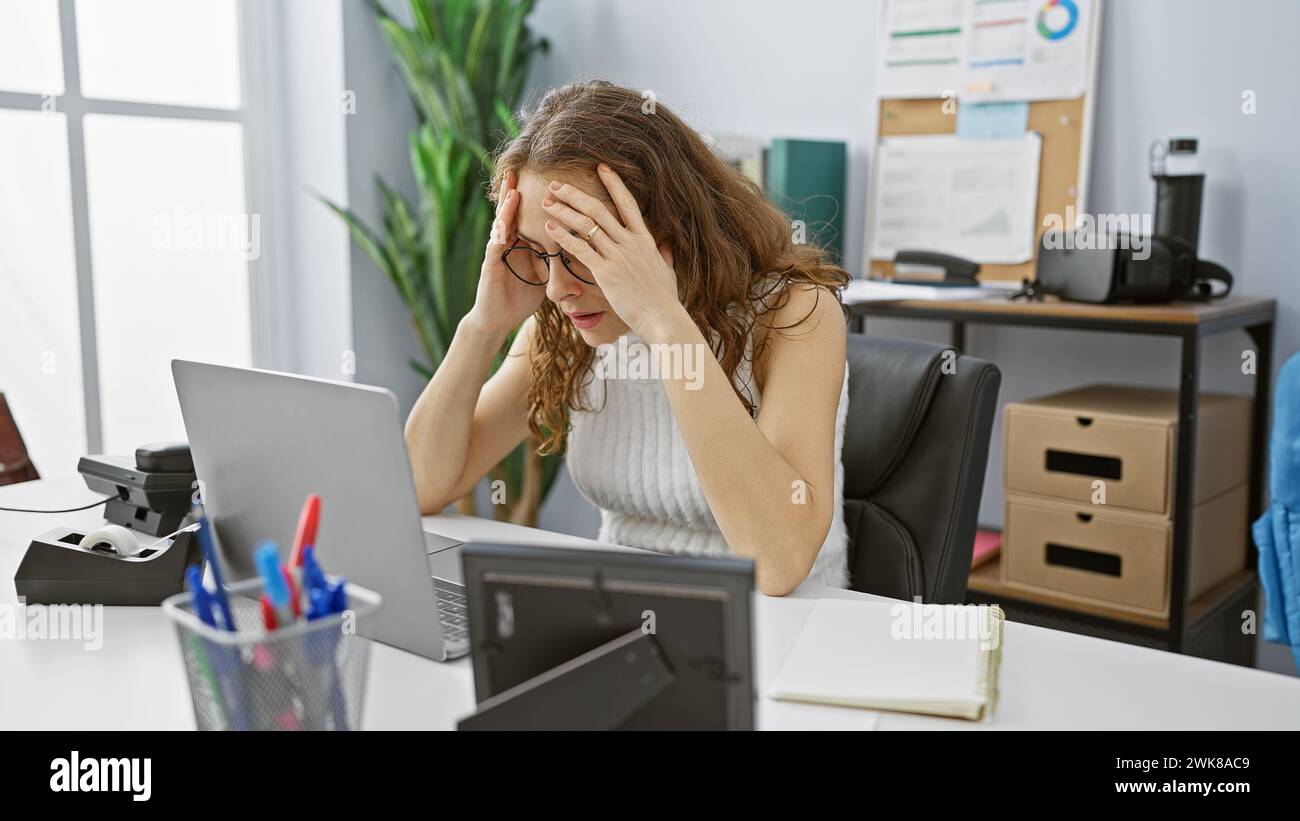 Stressed hispanic woman experiencing a headache at her office workplace ...