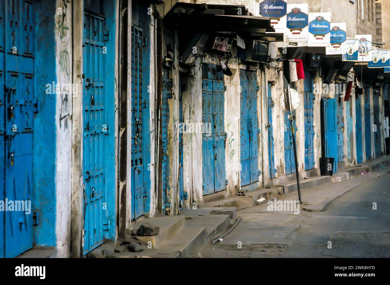 Sanaa, Yemen - July 1, 1991: closed shops in Sanaa with typical blue doors all with advertising for the cigatette brand Rothmans. Stock Photo