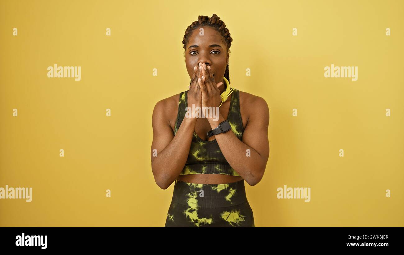 African american woman with braids wearing activewear poses against a ...