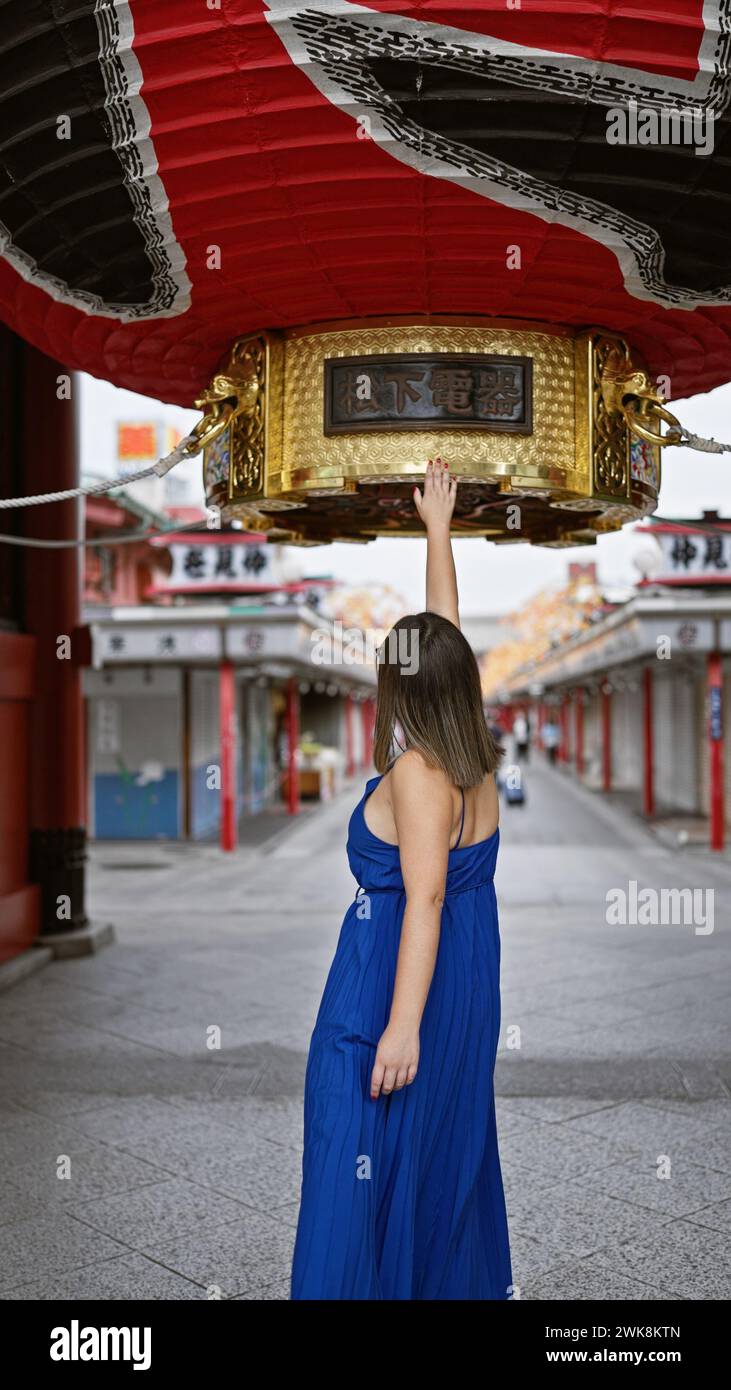 Cheerful hispanic female in glasses, charmed by colossal asian lantern at senso-ji temple, creates fantastic travel memories in tokyo's traditional cu Stock Photo