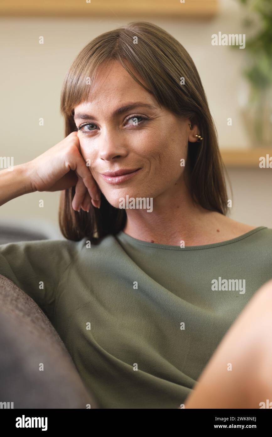 A smiling Caucasian woman with a relaxed posture is sitting comfortably Stock Photo