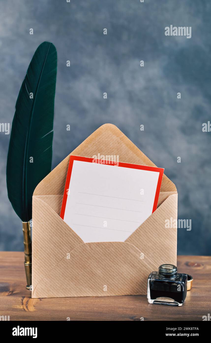 Vintage envelope with empty card and quill pen on wooden table Stock Photo