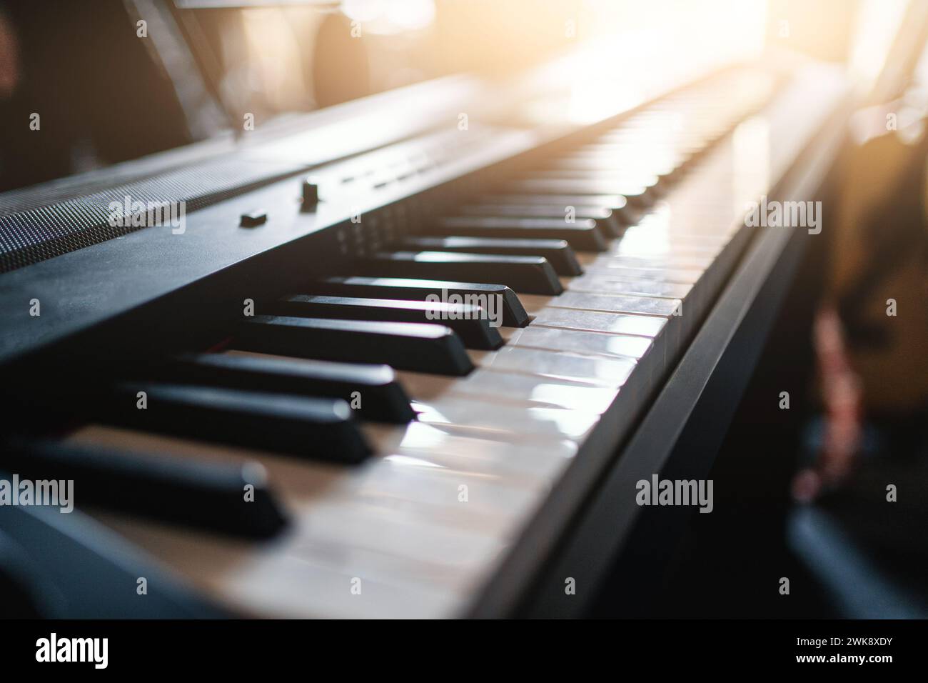 Closeup of piano keyboard with sunlight streaming through window, showcasing beauty of this musical instrument Stock Photo