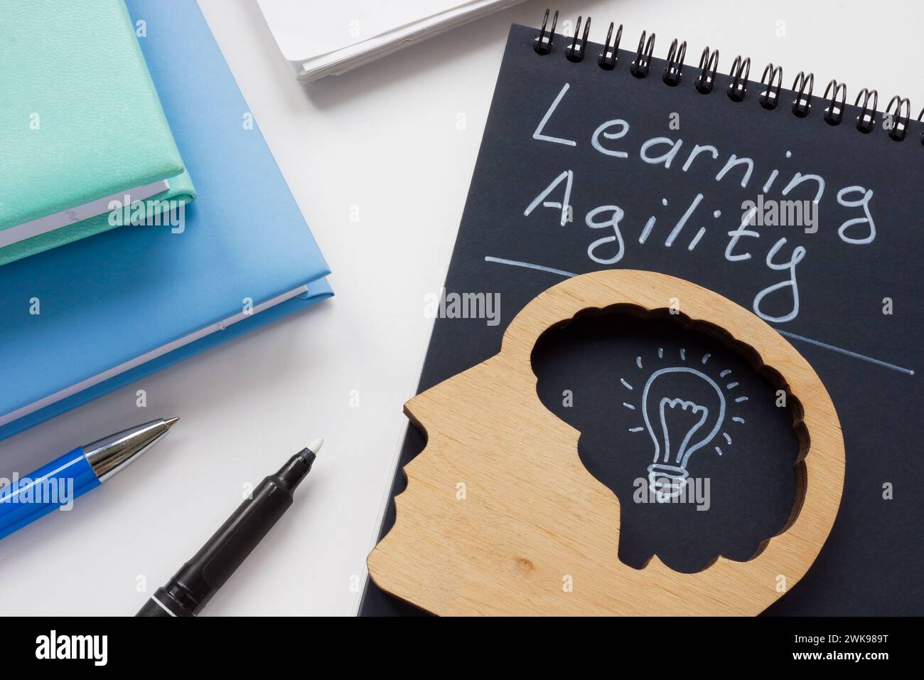 Notepad with inscription learning agility and head model. Stock Photo