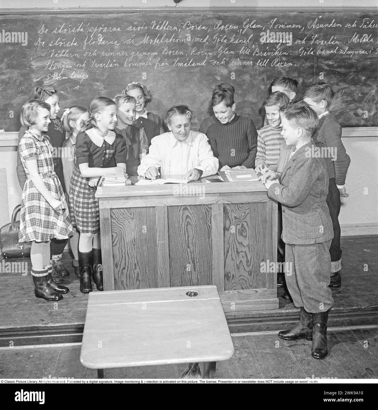 School in the 1950s. The female schoolteacher in the classroom with her students, all looking happy and laughing. Sweden 1950 Kristoffersson ref  BH11-11 *** Local Caption *** © Classic Picture Library. All rights reserved. Protected by a digital signature. Image monitoring & protection is activated on this picture. The license; Presentation or newsletter does NOT include usage on social media. Stock Photo