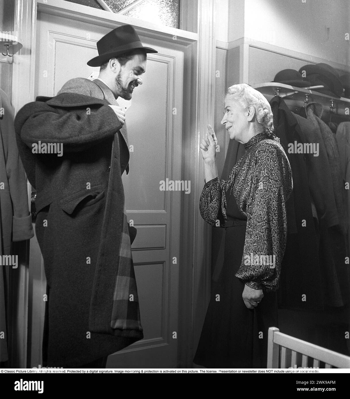In the 1940s. The landlady rises her finger to emphasize her words to the man putting his clothes on and just about to leave for an evening on the town. 'Don't be out too late, remember it's working day tomorrow'. 1949. Kristoffersson ref AN25-3 *** Local Caption *** © Classic Picture Library. All rights reserved. Protected by a digital signature. Image monitoring & protection is activated on this picture. The license; Presentation or newsletter does NOT include usage on social media. Stock Photo