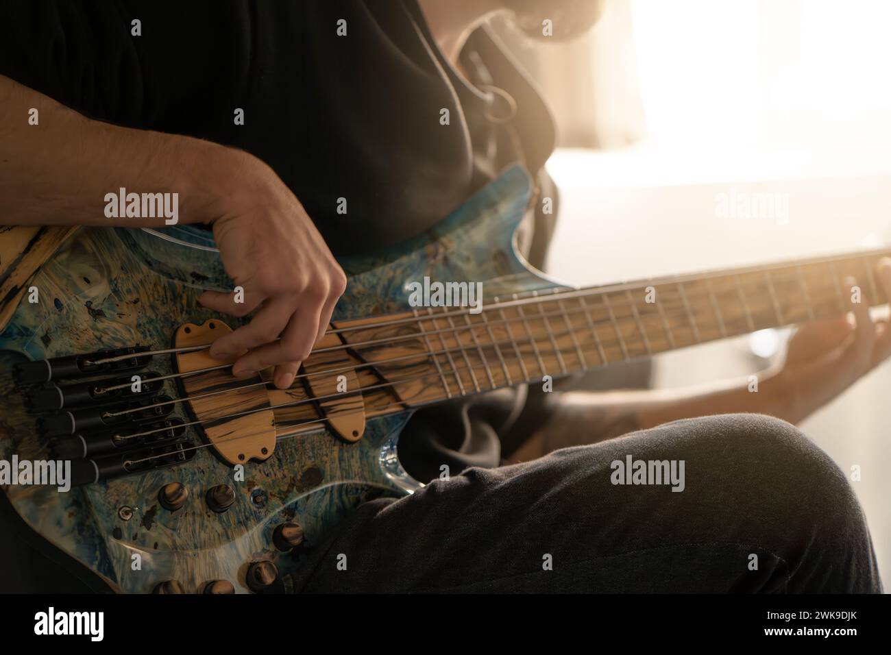 Close up of male hands playing bass guitar. His fingers on strings, creating music. Stock Photo