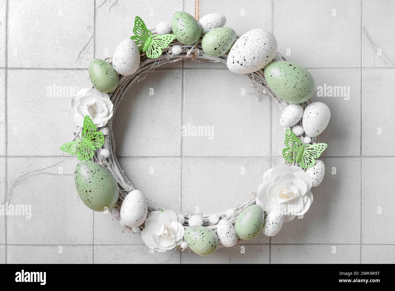 Easter wreath made of flowers, eggs and butterflies hanging on white ...