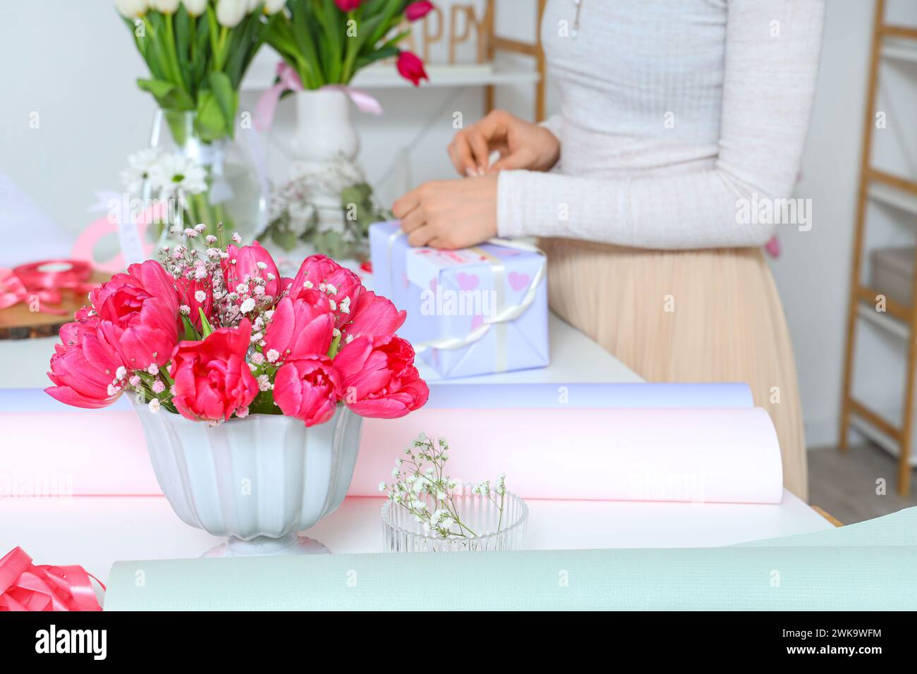 Woman packing gift box for International Women's Day at light table