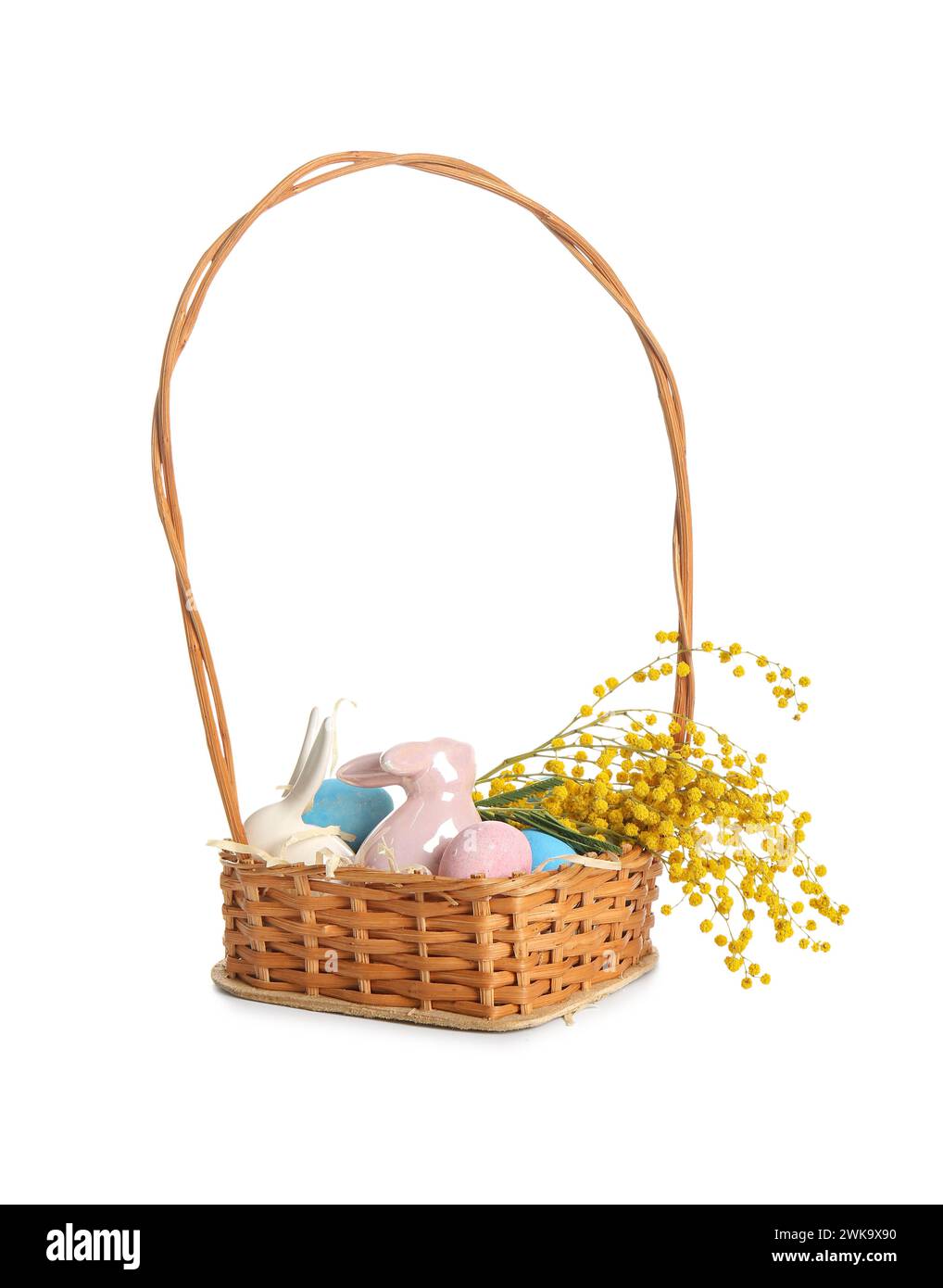 Wicker basket with painted Easter eggs, ceramic bunnies and flowers on ...