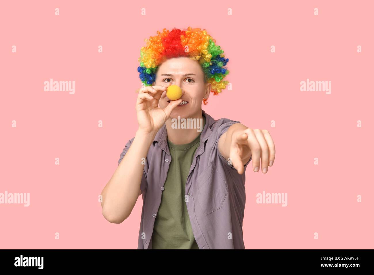 Handsome young man in funny disguise pointing at viewer on pink background. April fool's day celebration Stock Photo