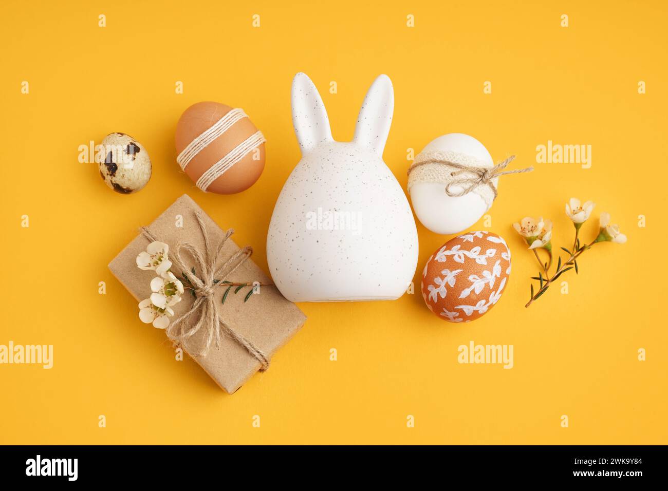 Decorated Easter eggs, bunny figure and present on yellow background Stock Photo