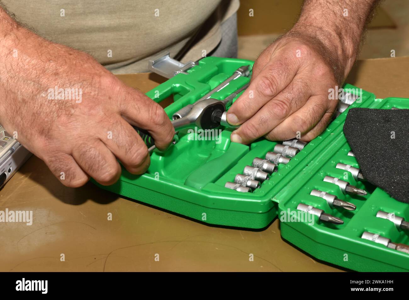 Close-up of the hands of a worker who prepares a locksmith's ratchet wrench for work, he connects the wrench to the socket head. Stock Photo
