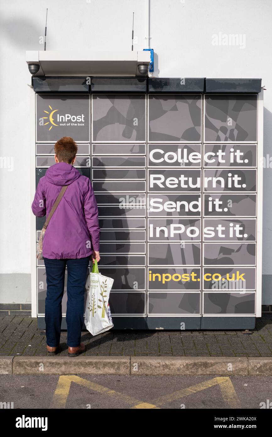 A customer delivers or collects a parcel to an inpost locker after completing a sale. A UK drop and collect service for parcel deliveries Stock Photo