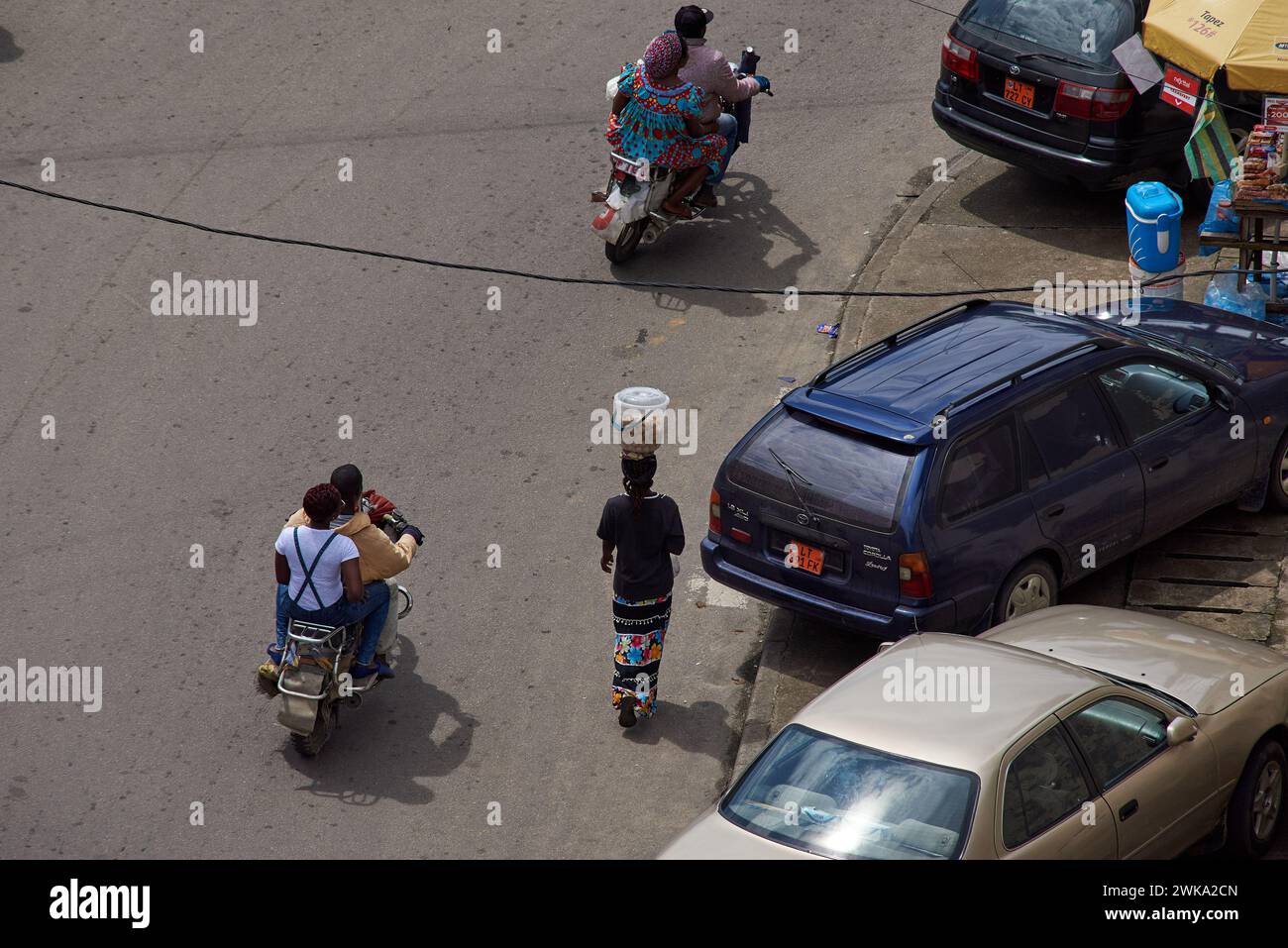 Woman carrying a basket on her head in the streets of Douala Stock Photo