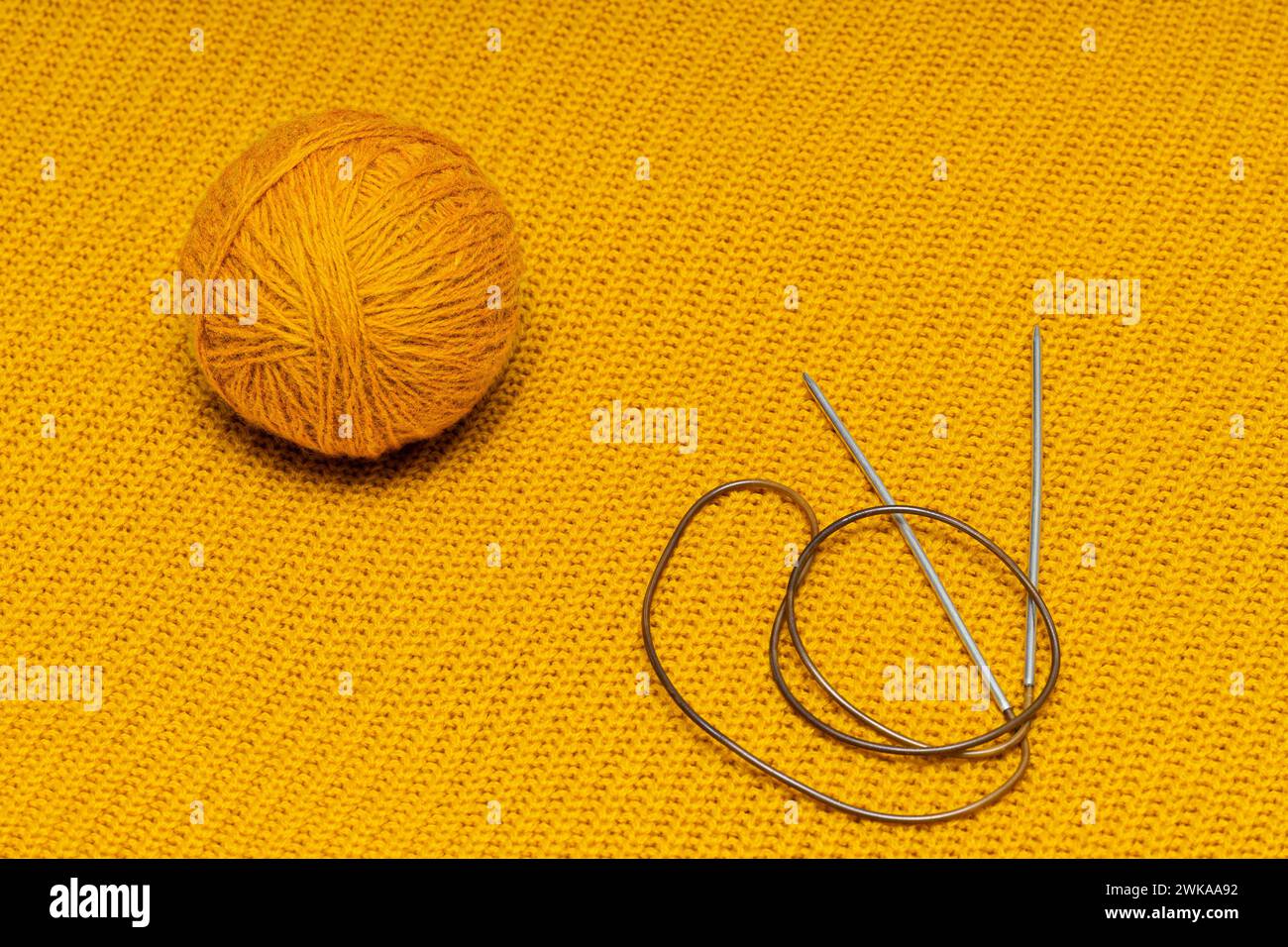 knitting needles and wool threads on a knitted background. knitting a ...