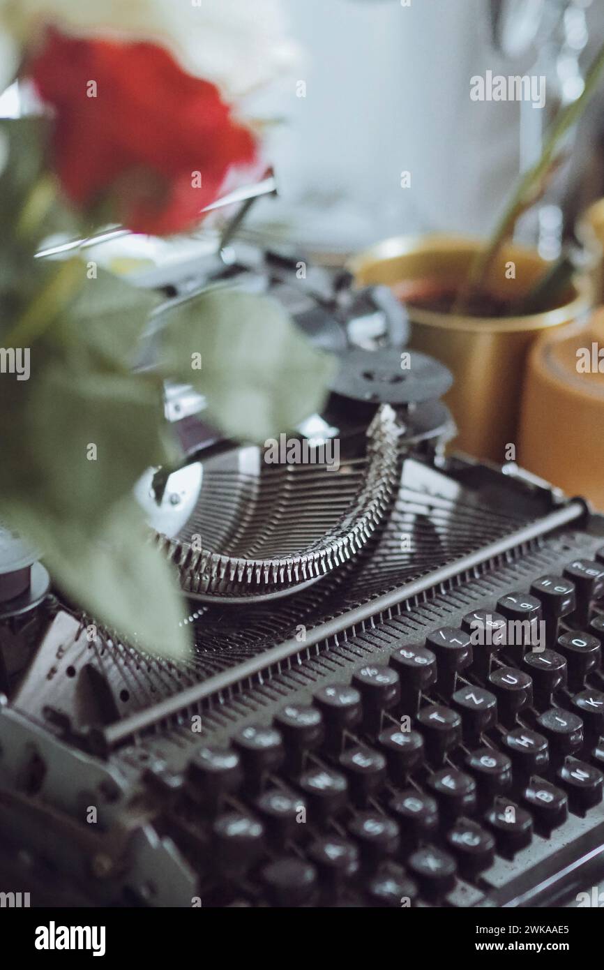 A vintage typewriter and a delicate rose placed together on a desk Stock Photo