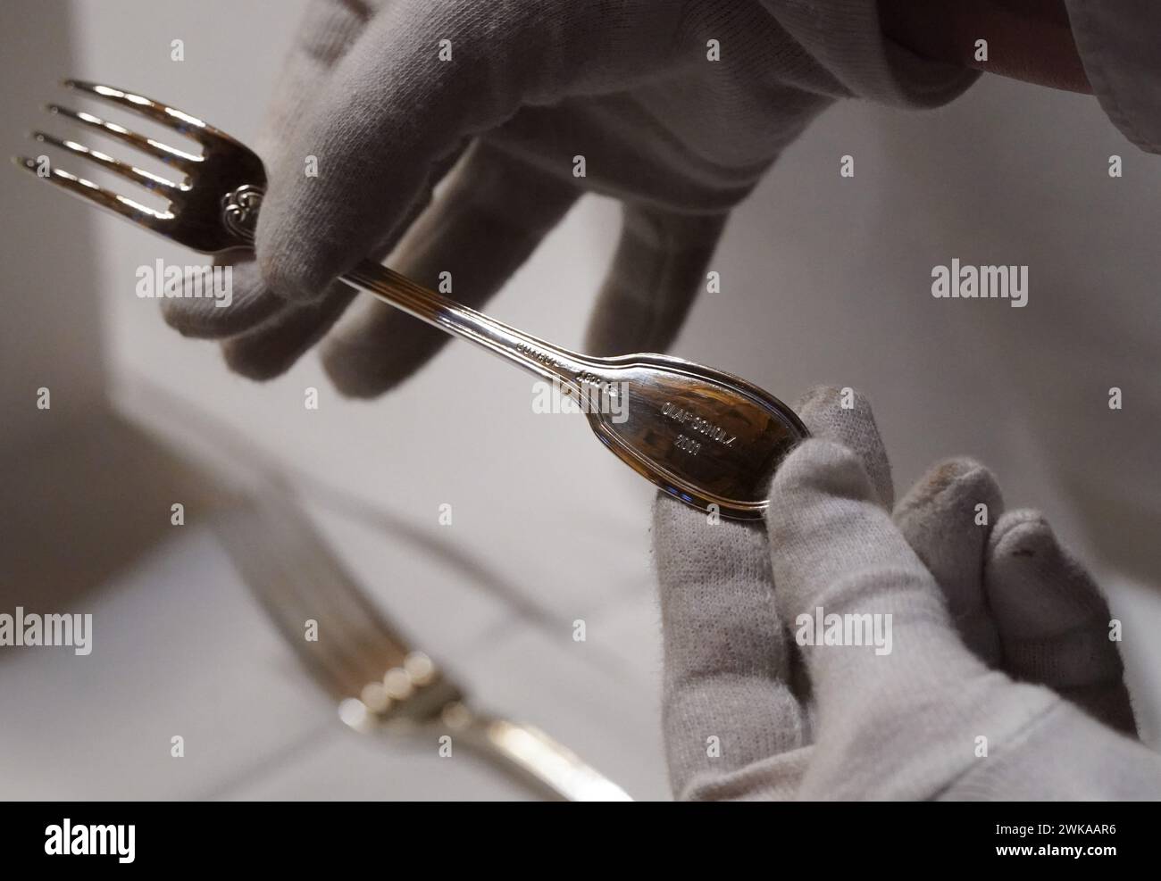 Hamburg, Germany. 19th Feb, 2024. A council servant holds a fork engraved with 'Olaf Scholz' in the large banquet hall during the final preparations for the traditional Matthiae meal of the Hamburg Senate in City Hall. The Prime Minister of the Republic of Estonia, Kallas, and Federal Chancellor Scholz are expected to attend the Matthiae meal as guests of honor. The Matthiae banquet is considered to be the oldest still celebrated banquet in the world. Credit: Marcus Brandt/dpa/Alamy Live News Stock Photo