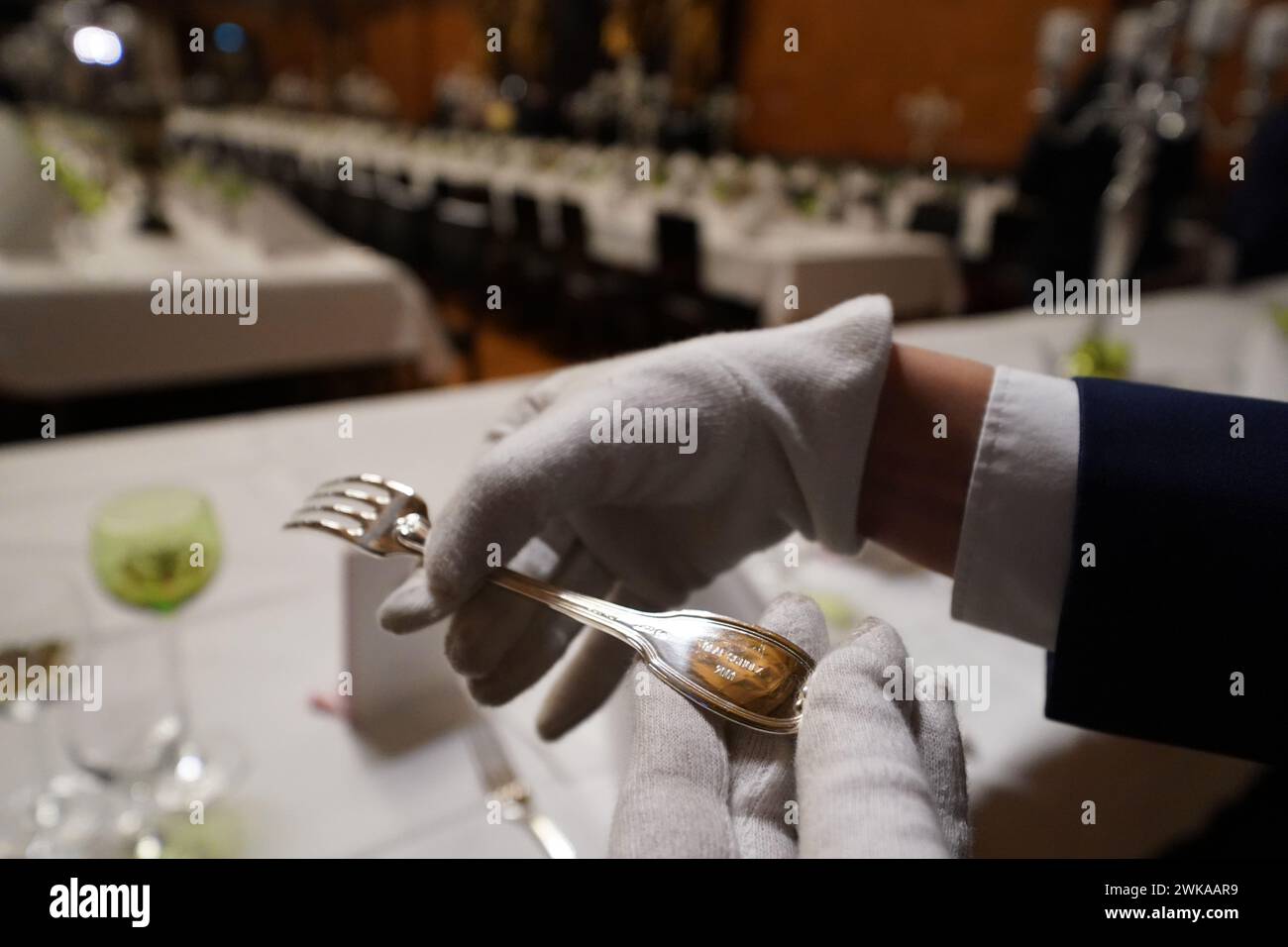 Hamburg, Germany. 19th Feb, 2024. A council servant holds a fork engraved with 'Olaf Scholz' in the large banquet hall during the final preparations for the traditional Matthiae meal of the Hamburg Senate in City Hall. The Prime Minister of the Republic of Estonia, Kallas, and Federal Chancellor Scholz are expected to attend the Matthiae meal as guests of honor. The Matthiae banquet is considered to be the oldest still celebrated banquet in the world. Credit: Marcus Brandt/dpa/Alamy Live News Stock Photo