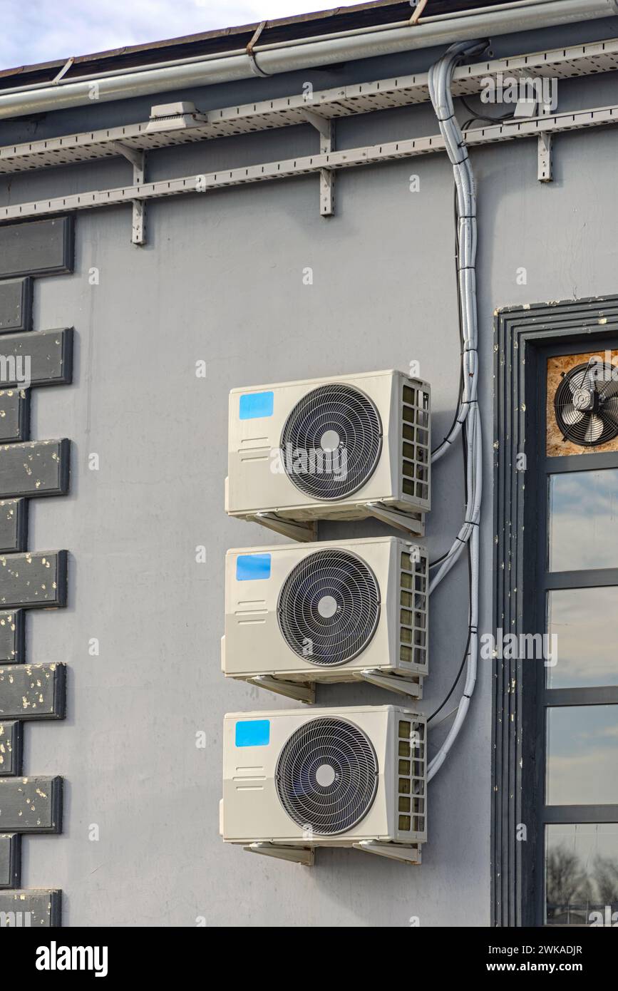 Three Split Air Conditioners System Condenser Units at Industrial Building Wall Stock Photo
