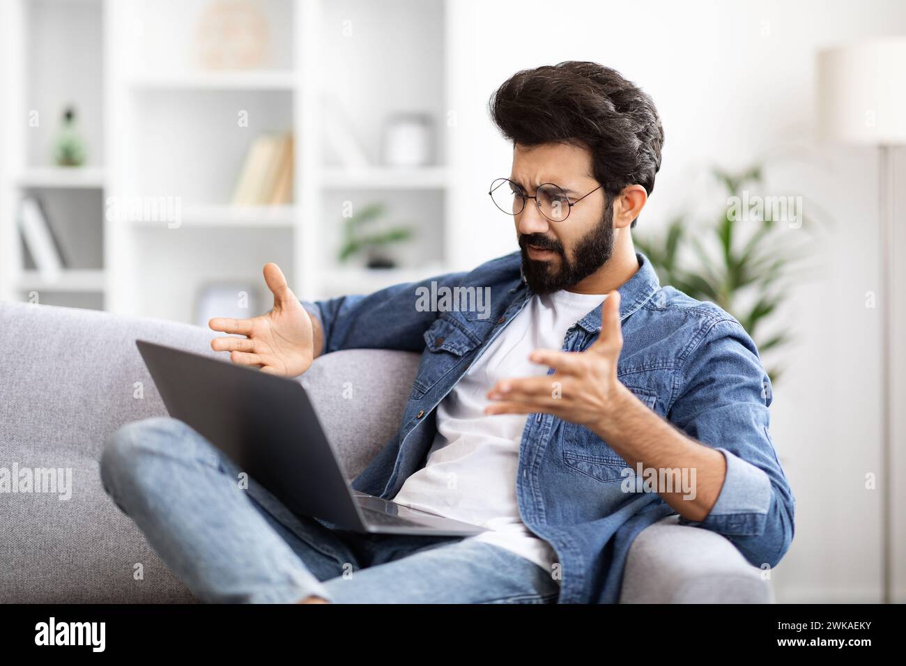 Confused Young Indian Guy Suffering Problems While Using Laptop At Home Stock Photo