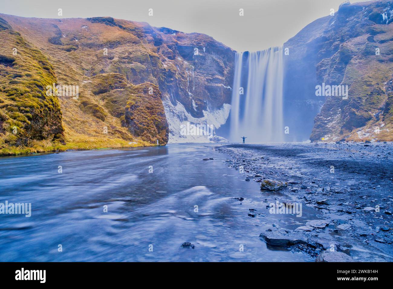 Skogafoss waterfall Iceland in winter with loan person standing in front of waterfall Stock Photo