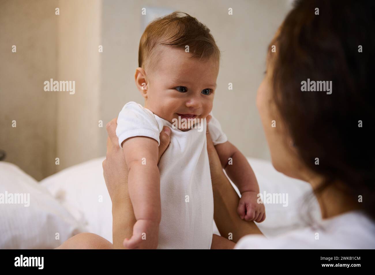 Happy excited newborn baby laughing at mother face, showing positive