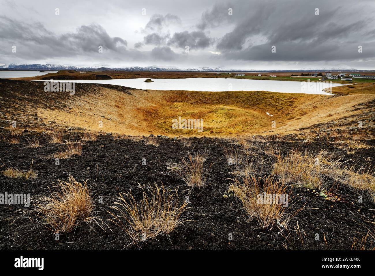 Large rootless cone formed from a steam explosion over a lava flow, with large tufts of grass on black volcanic ash and larger areas of grass Stock Photo