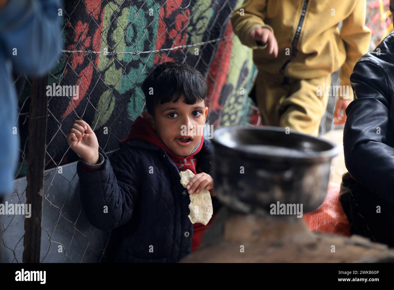 Gaza. 18th Feb, 2024. A Palestinian boy eats a piece of bread at a temporary camp in the southern Gaza Strip city of Rafah, on Feb. 18, 2024. Over the past few weeks, Israel has signaled its intention to conduct a ground operation in Rafah, Gaza's southernmost town, to 'eliminate' Hamas and rescue Israeli hostages. The impending invasion has deeply concerned the international community. Several countries have spoken out against it, warning of a humanitarian catastrophe in the coastal enclave. Credit: Yasser Qudih/Xinhua/Alamy Live News Stock Photo