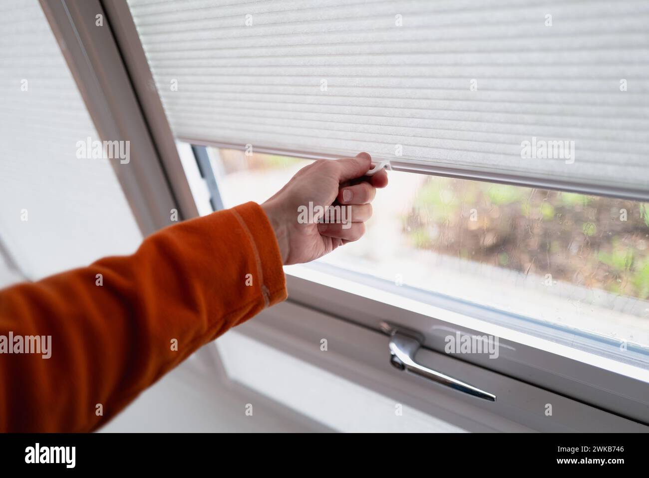 Hand holding the handle of made to measure conservatory blinds that slide up and down. Shallow focus. Stock Photo