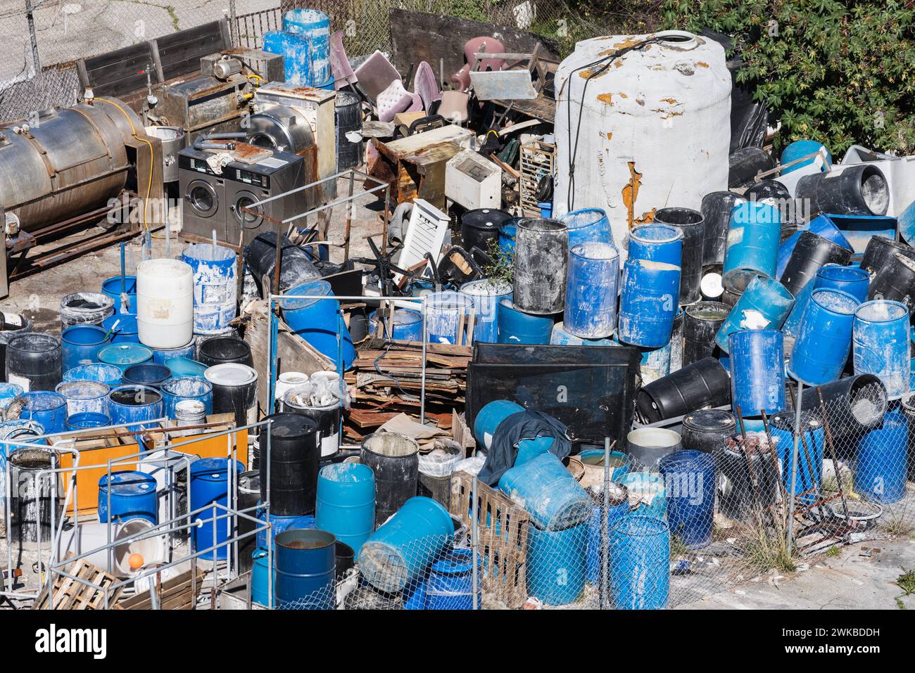 Pile of scary industrial waste barrels, trash and debris in an open outdoor lot. Stock Photo