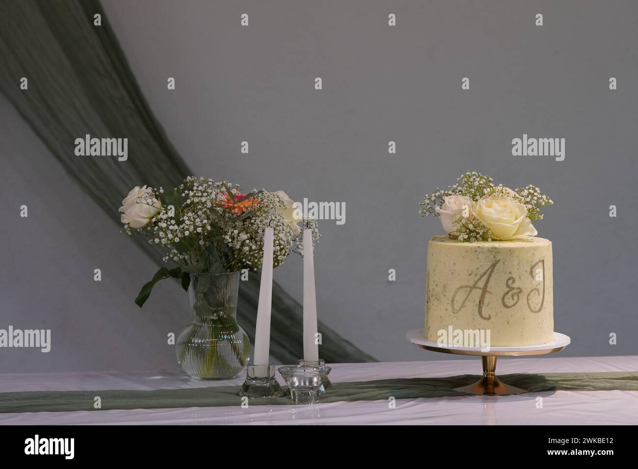 The wedding cake adorned with delicate flowers and featuring the initials A&J or A&I adds an elegant touch to the celebration. Stock Photo