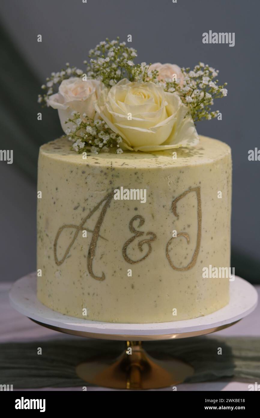 The wedding cake adorned with delicate flowers and featuring the initials A&J or A&I adds an elegant touch to the celebration. Stock Photo