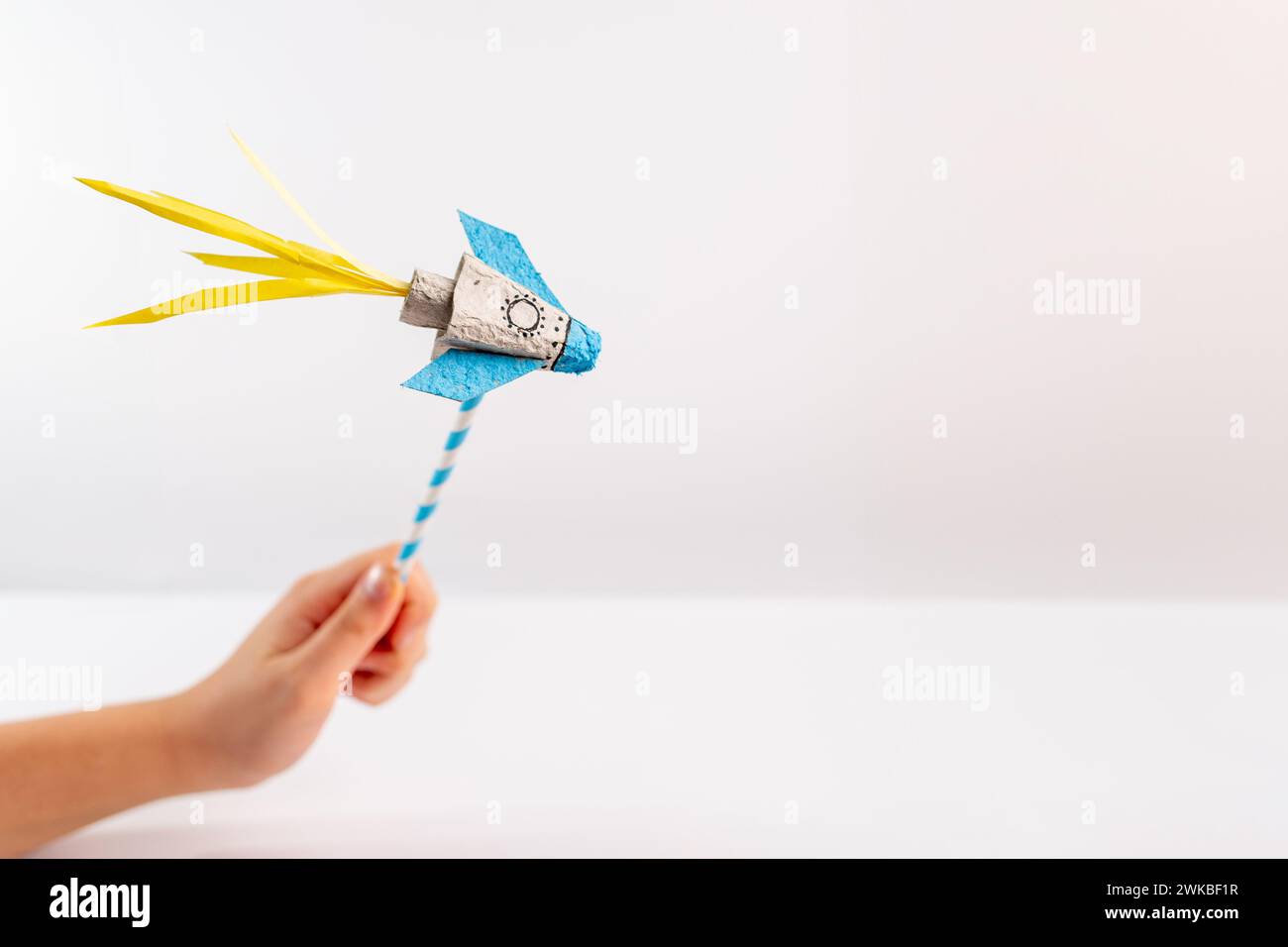 a close up of a person holding a paper rocket, with a white background ...