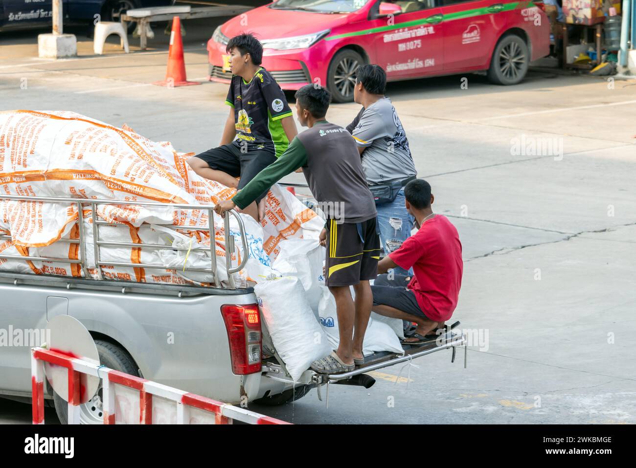 SAMUT PRAKAN, THAILAND, NOV 03 2023, A group of men is driving with a load on a pickup truck Stock Photo