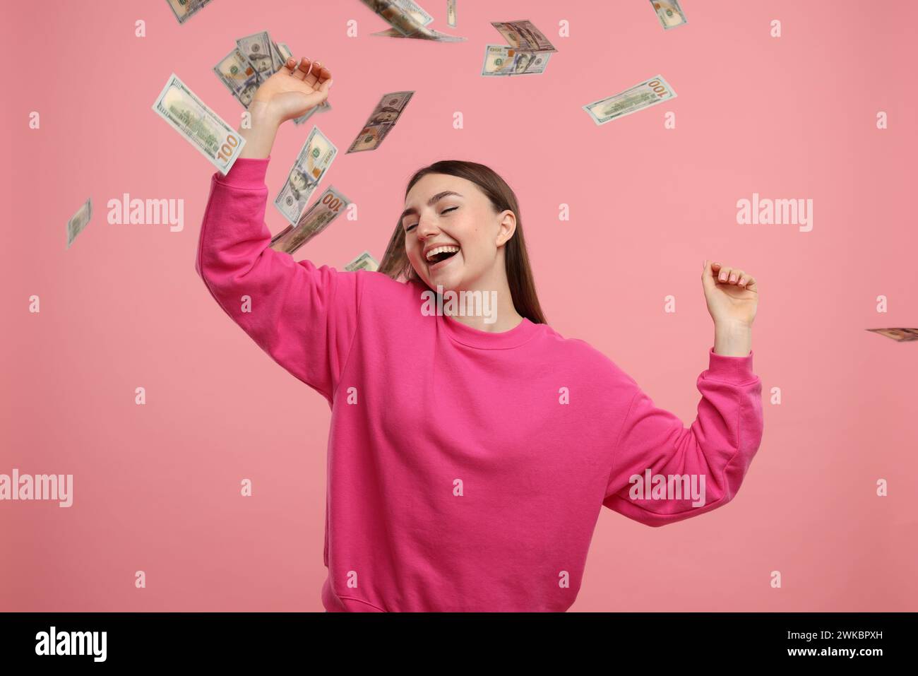 Happy woman under money shower on pink background Stock Photo