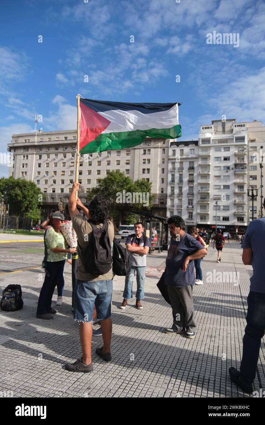 Buenos Aires, Argentina, Feb 16, 2024: Man raising a Palestinian flag, people gathered in front of the National Congress in support and solidarity wit Stock Photo