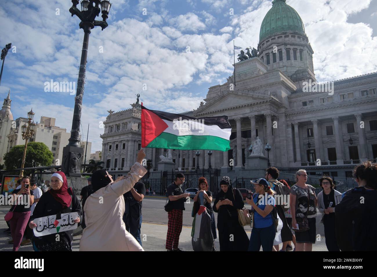 Buenos Aires, Argentina, Feb 16, 2024: Woman raising a Palestinian flag, people gathered in front of the National Congress in solidarity with Palestin Stock Photo