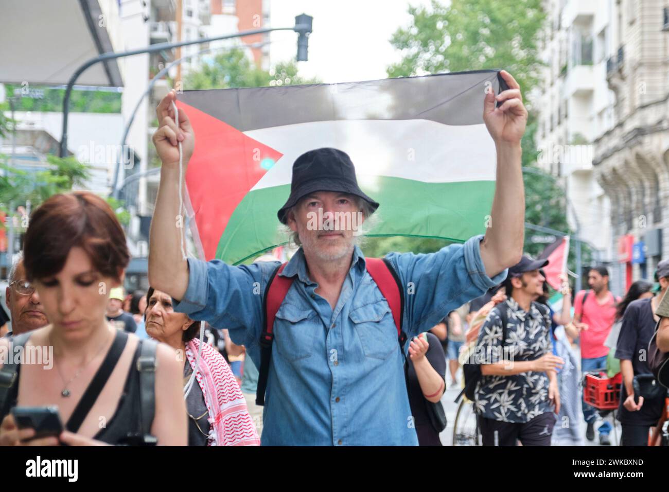 Buenos Aires, Argentina, Feb 16, 2024: Man raising a Palestinian flag, marching in support and solidarity with Palestine and against Israel genocide a Stock Photo