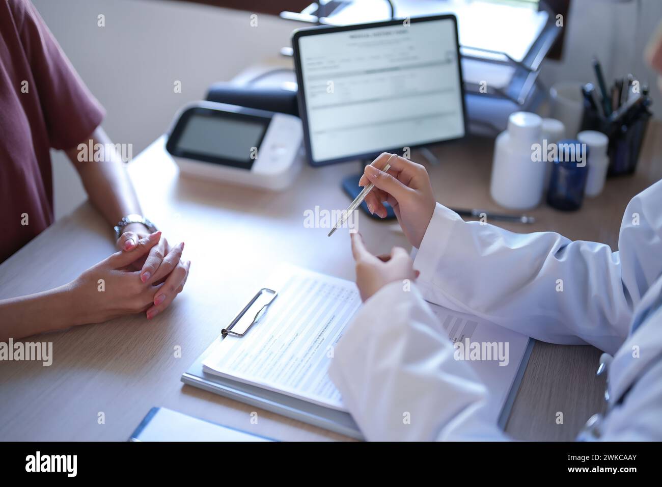 Asian psychologist women showing thermometer to explaining for reading temperature results about testing fever to patient while giving counseling ment Stock Photo