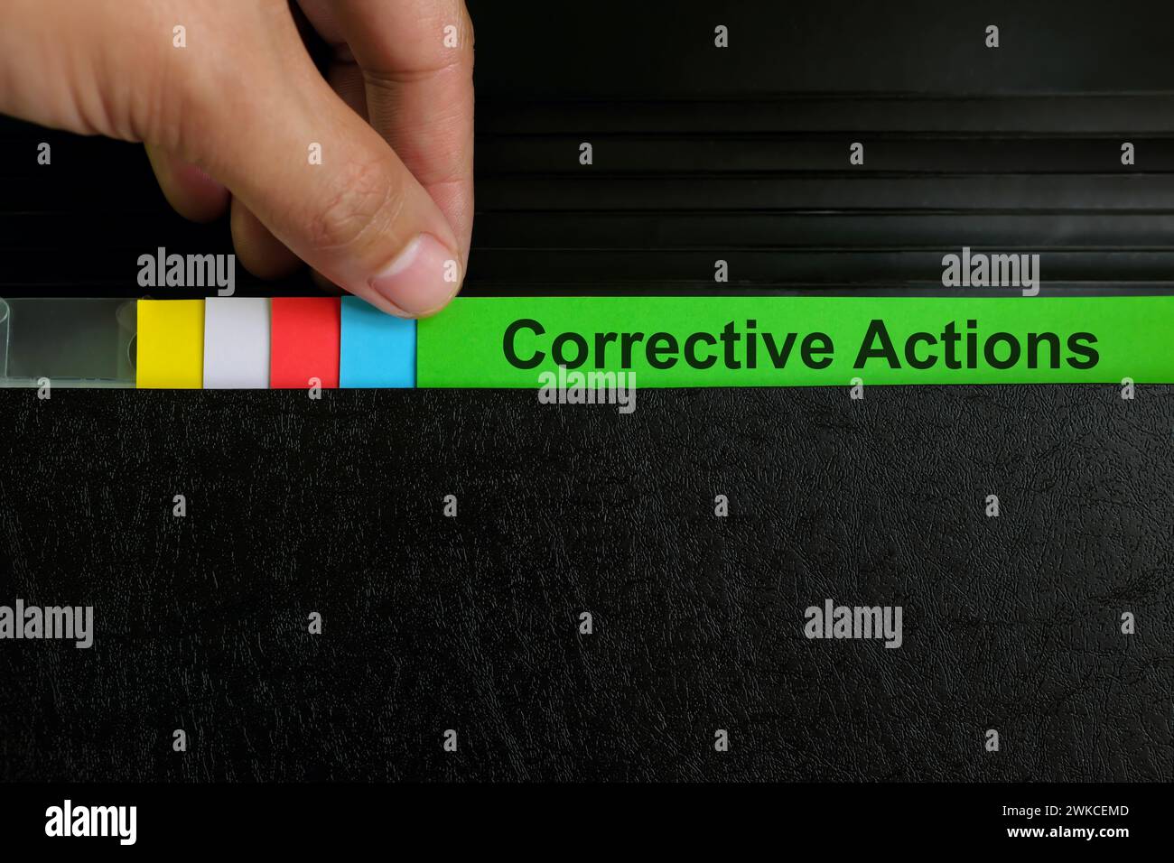 Hand picking corrective action file organizer in black background. Audit findings and root cause analysis concept. Stock Photo