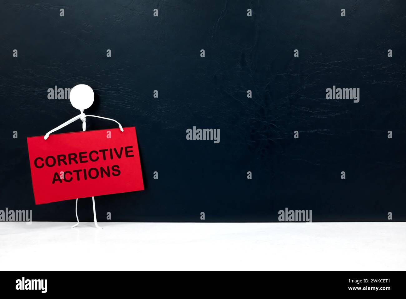 Stick figure holding corrective action placard in black background. Audit findings and root cause analysis concept. Stock Photo