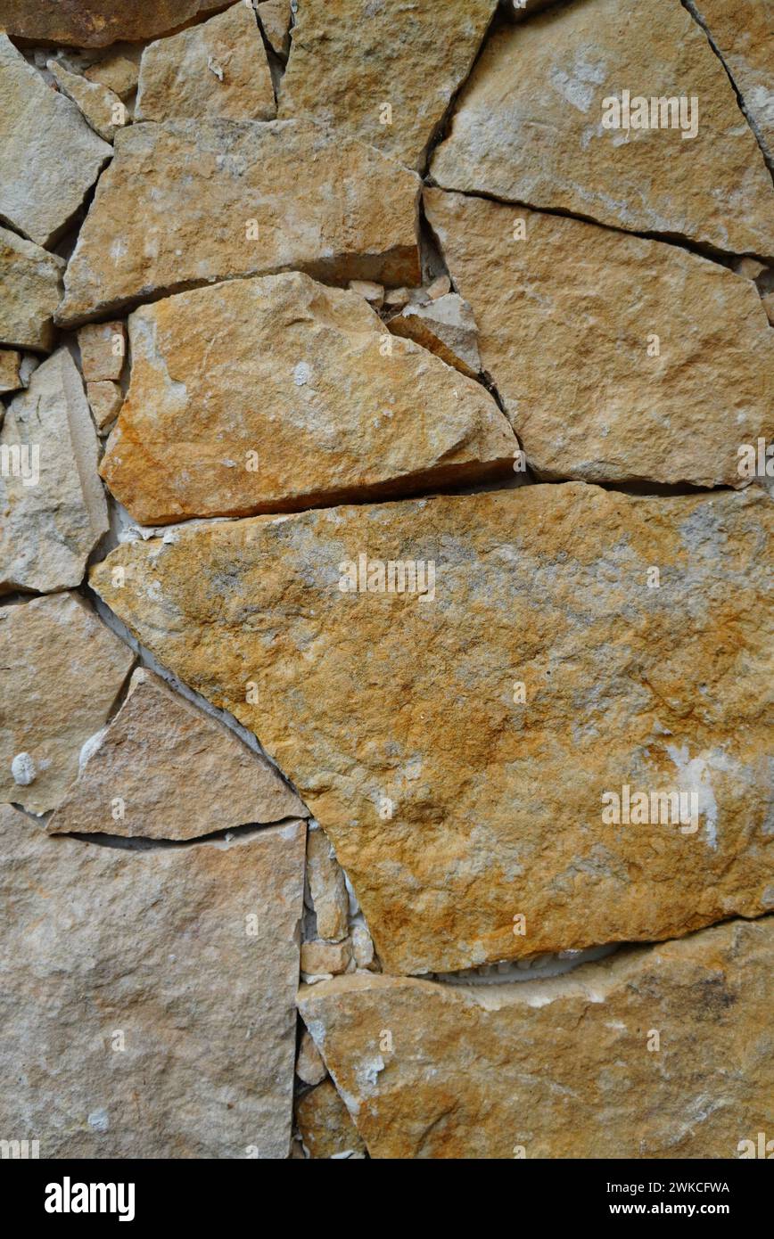 An ancient weathered stone wall with numerous cracks and chips Stock Photo