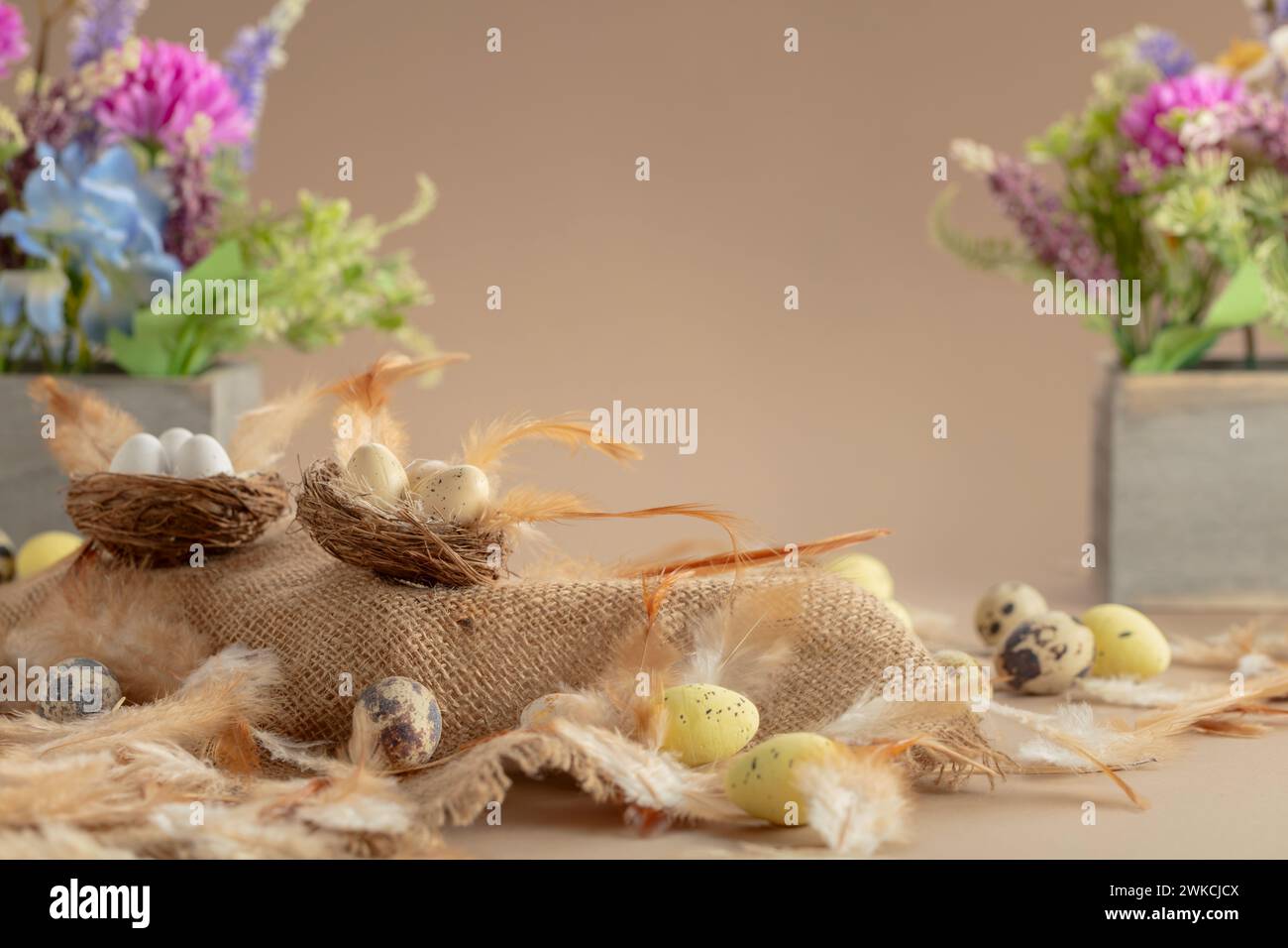 Easter composition with eggs, feathers, and spring flowers on a beige ...