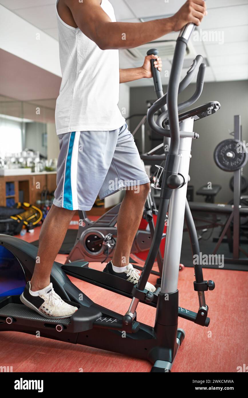 Fitness, legs and air walker with man in gym for health, wellness or workout to improve cardio. Exercise, running and sports with athlete on glider Stock Photo