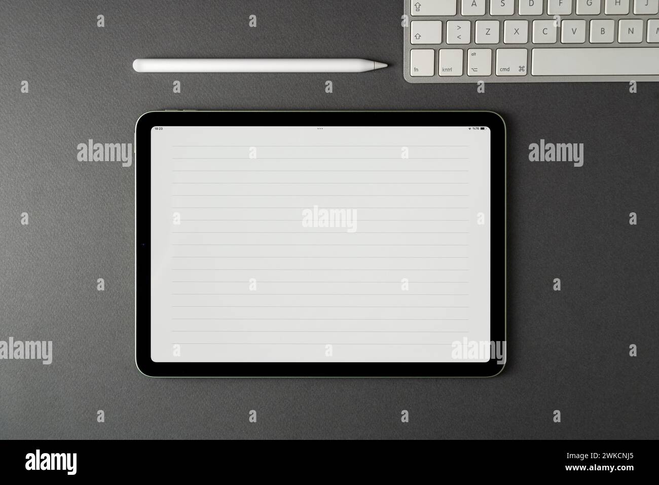 Tablet with lined notepaper on the screen and a keyboard and stylus pen on a dark gray table Stock Photo