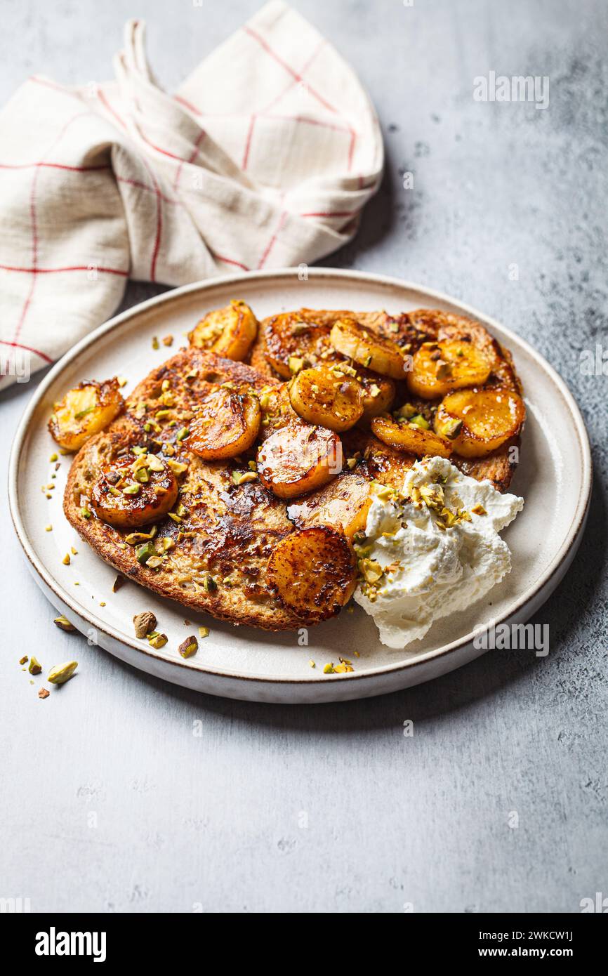 French toasts with caramelized banana and pistachios. Stock Photo