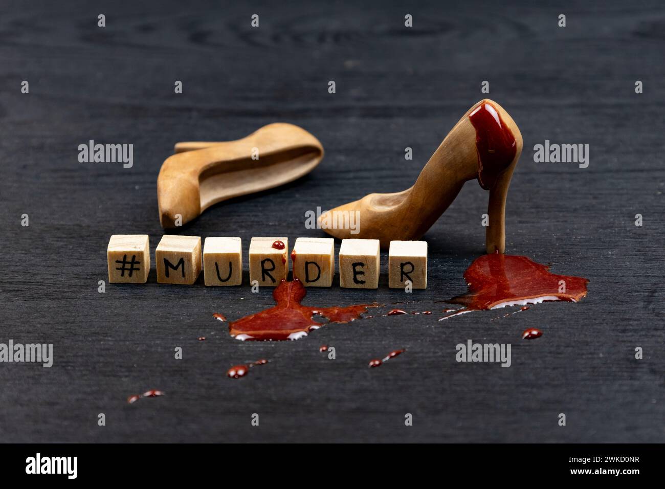 Conceptually photo with Beautiful fashion wood female shoes with drop of the blood on it. The wooden cubes with word MURDER on the dark background wit Stock Photo